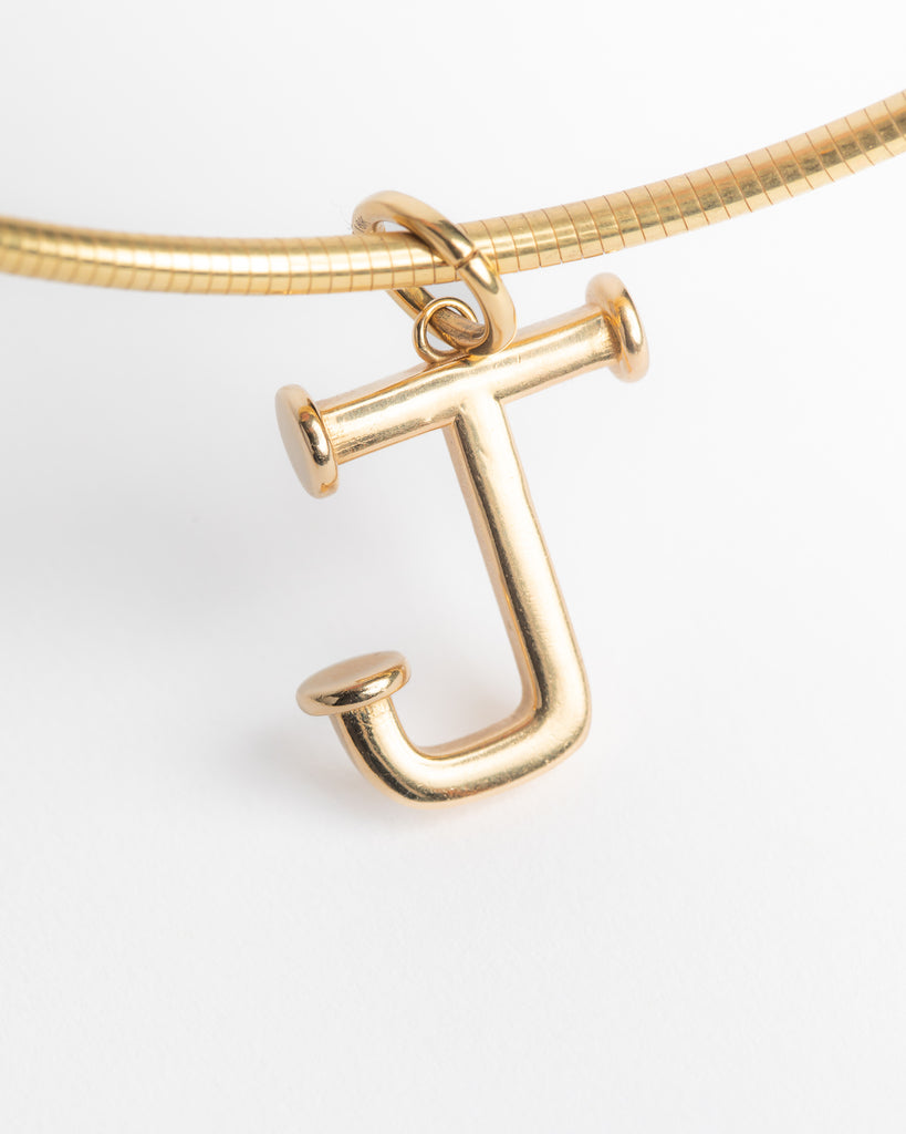 Gold necklace with a letter 'J' pendant on a light gray background