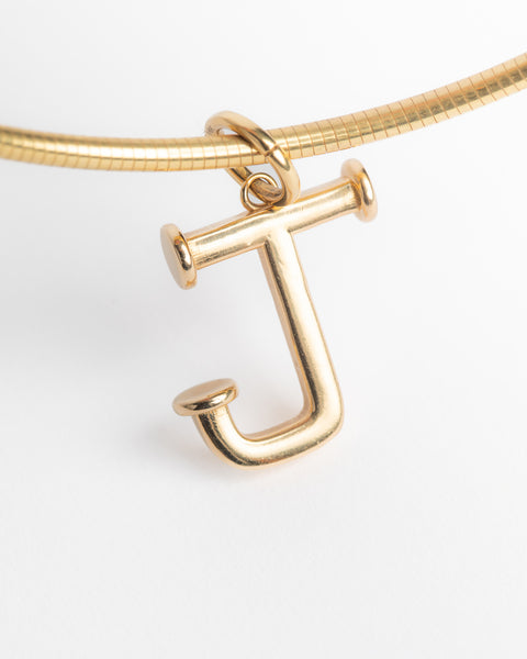 Gold necklace with a letter 'J' pendant on a light gray background