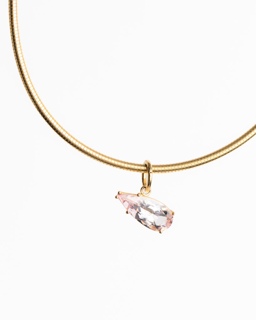 Gold necklace with a pink gemstone pendant on a white background
