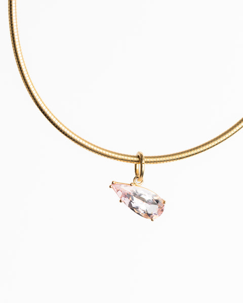 Gold necklace with a pink gemstone pendant on a white background