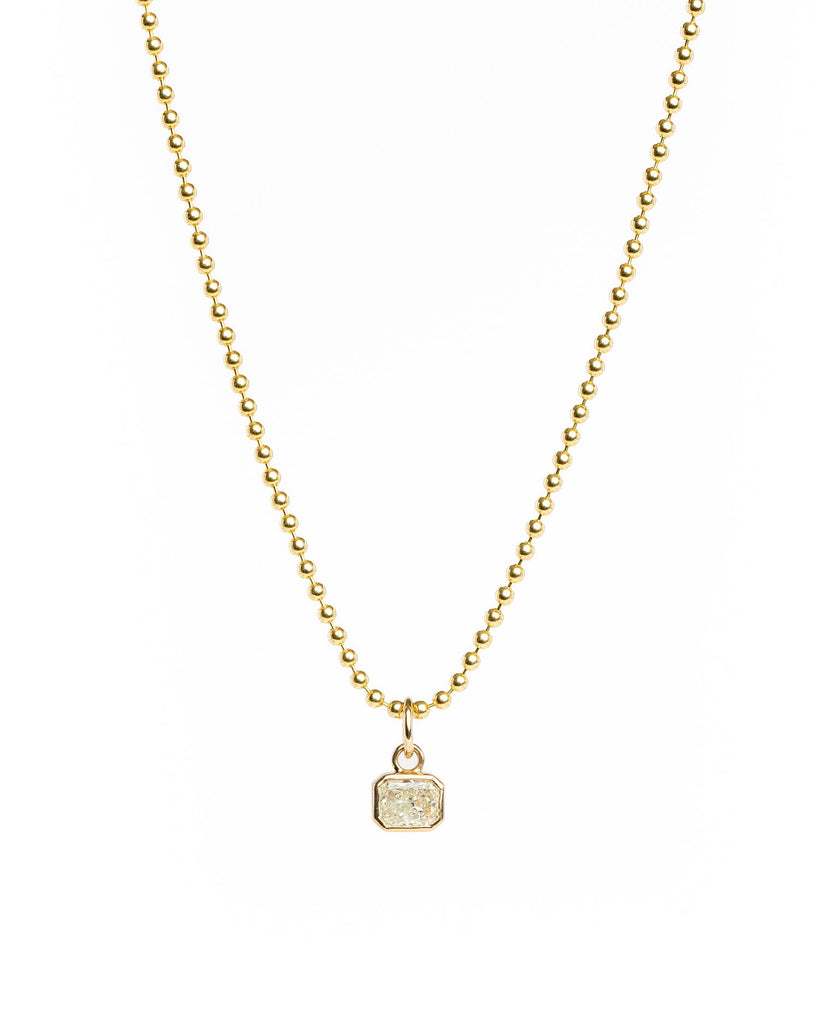 Gold necklace with a small pendant on a white background